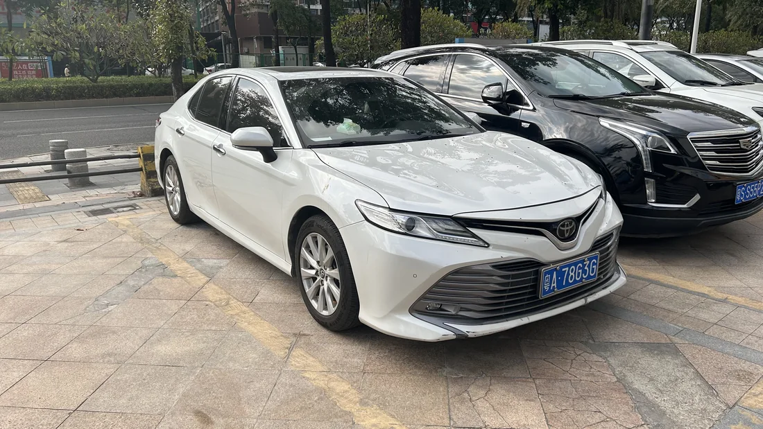 White Toyota Camry sedan photographed from the front and side.